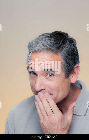 Ritratto in studio di uomo maturo che copre la bocca con la mano Foto Stock