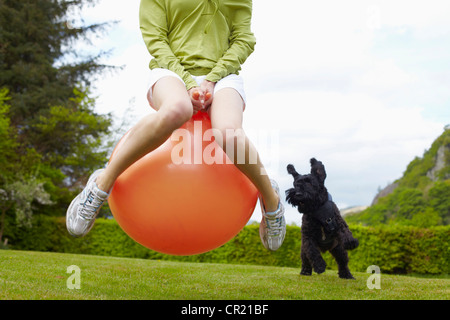 Donna su bouncy sfera di gioco con il cane Foto Stock