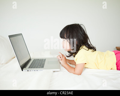 Ragazza sdraiati a letto, utilizzando laptop (4-5) Foto Stock