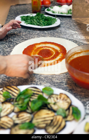 Lo Chef diffondendo in salsa di impasto per pizza Foto Stock