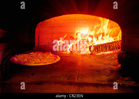 La cottura della pizza nel forno a legna Foto Stock