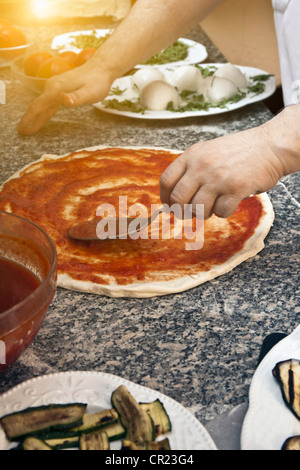 Lo Chef diffondendo in salsa di impasto per pizza Foto Stock