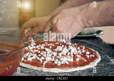 Lo Chef spolverata formaggio sulla pizza cruda Foto Stock