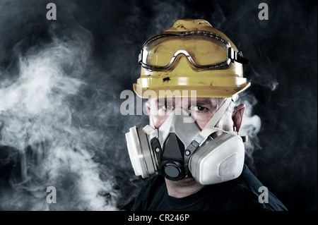 Un lavoratore di salvataggio indossa un respiratore in smokey, atmosfera tossica. L'immagine mostra l'importanza della disponibilità di protezione e sicurezza. Foto Stock