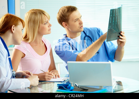 Ritratto di giovane medico commentando x-ray risultati esame al suo collega e il paziente Foto Stock