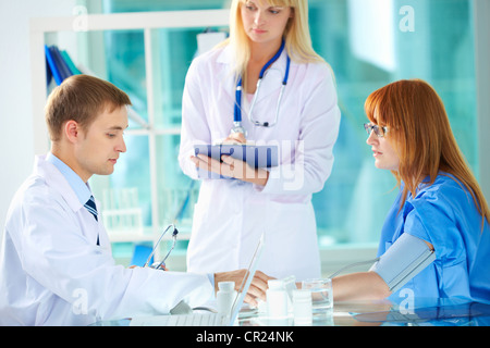 Ritratto di fiducioso praticante la misura della pressione del sangue in ospedale Foto Stock