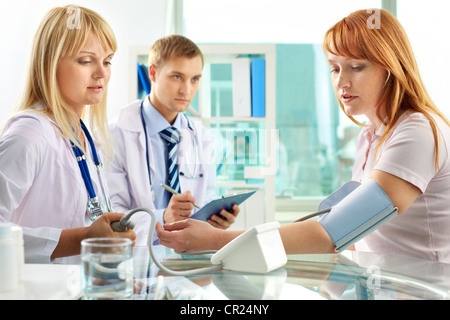 Ritratto di fiducioso praticante la misura della pressione del sangue in ospedale Foto Stock
