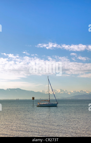 Una solitaria barca a vela al mattino su di un lago calmo Foto Stock