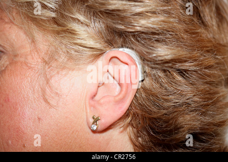 Signora indossando un digital dietro l'orecchio Hearing Aid Foto Stock