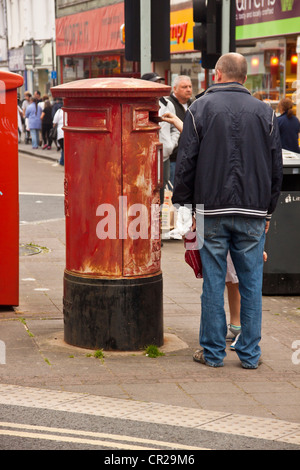 Vecchio rosso casella postale nella necessità di riverniciatura, Newton Abbot, Devon, Regno Unito. Foto Stock