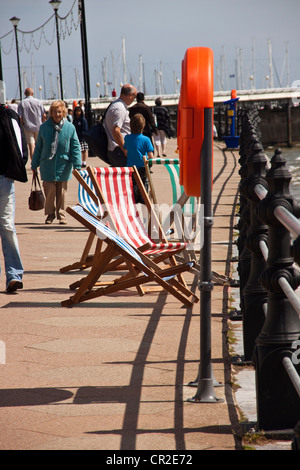 Vuoto sedie a sdraio su Torquay fronte mare soffiando nel vento brezza. Foto Stock