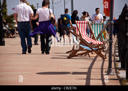 Vuoto sedie a sdraio su Torquay fronte mare soffiando nel vento brezza. Foto Stock