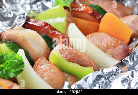 La carne di maiale e spiedini di vegetali in lamina di alluminio Foto Stock