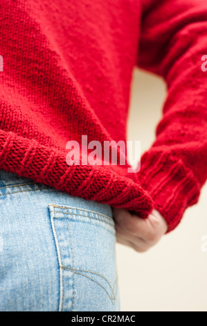 Abstract di uomo a mettere su un rosso, mano a maglia il ponticello Foto Stock