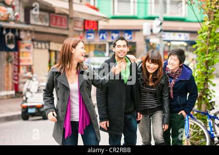 Un gruppo di amici passeggiate lungo una strada di Tokyo Foto Stock