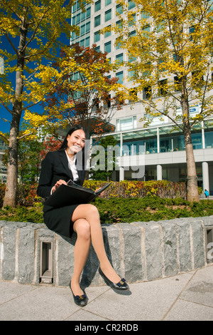 Donna seduta all'aperto in business park Foto Stock