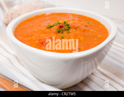 Una ciotola di lenticchie e zuppa di pomodoro guarnita con erba cipollina. Foto Stock