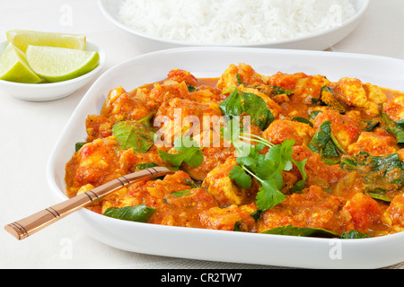 Sag di pollo o saag, speziato al piatto di pollo con baby spinaci, servito con riso basmati e calce. Foto Stock