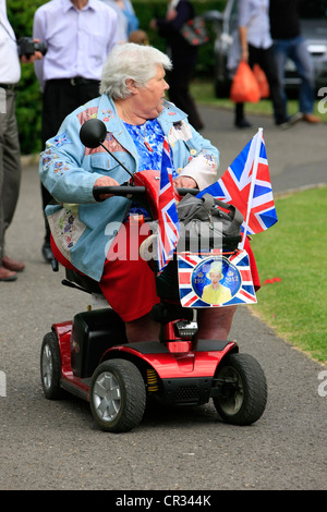 Femmina Senior passeggiate intorno nel suo scooter essendo patriottici sul Giubileo weekend in Inghilterra Foto Stock