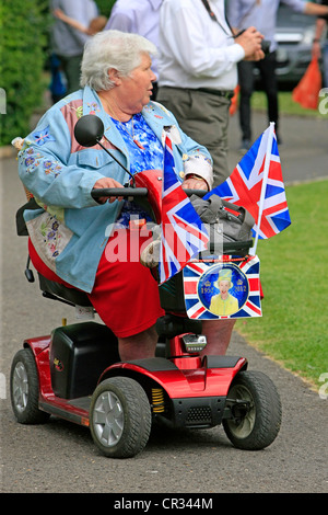 Femmina Senior passeggiate intorno nel suo scooter essendo patriottici sul Giubileo weekend in Inghilterra Foto Stock