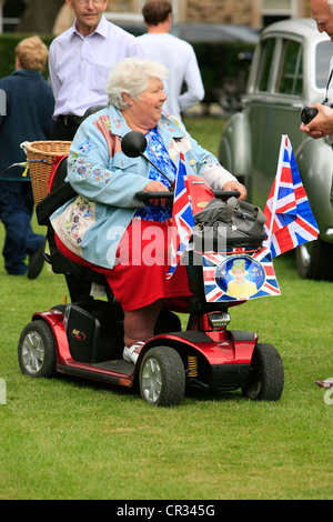 Femmina Senior passeggiate intorno nel suo scooter essendo patriottici sul Giubileo weekend in Inghilterra Foto Stock