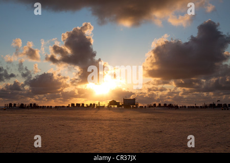 Silhouette di palafitte sulla spiaggia di San Peter-Ording al tramonto, Sankt Peter-Ording, Nord distretto Friesland Foto Stock