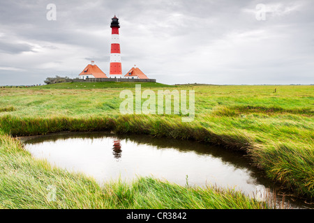 Faro di Westerheversand in mezzo alle saline con la sua riflessione in una insenatura di marea, Frisia settentrionale, Schleswig-Holstein Foto Stock