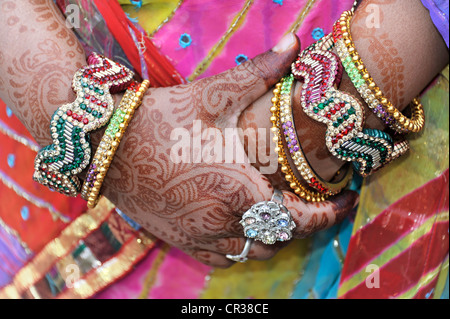 Festive henna pittura sulle mani di una donna indiana, donna che indossa gioielli per celebrare il quinto anniversario di matrimonio Foto Stock