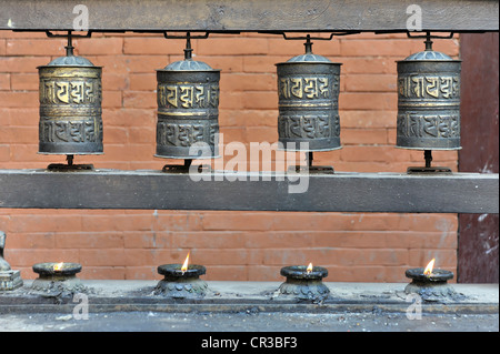 Una fila di lampade a burro e ruote della preghiera presso il Tempio d'oro, un tempio buddista a Patan, Nepal, Asia Foto Stock