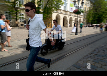 Pedoni e di un ciclomotore nella città vecchia, Lviv, Ucraina Foto Stock