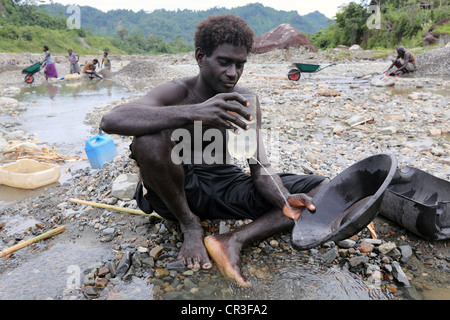 Uomo in oro di panning in inquinato Jaba fiume che scorre da Panguna miniera di rame. Regione autonoma di Bougainville, PNG Foto Stock