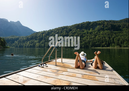 Le giovani donne che giace su di un pontile sul lago Schwansee vicino a Füssen, Allgaeu regione Baviera, Germania, Europa Foto Stock