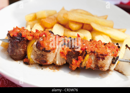 Spiedino di carne con peperoni gialli, cipolle e spezie argentino e patatine fritte Foto Stock