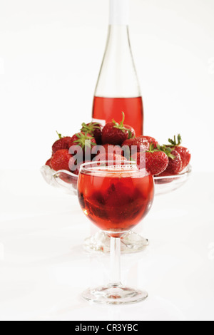 Bicchiere di vino Fragole nella parte anteriore del contenitore in vetro con fragole e una bottiglia di vino di fragole Foto Stock