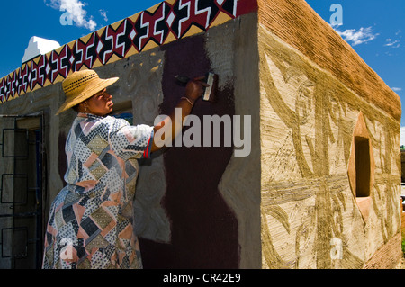 Donna della pittura la facciata di una casa, Basotho Villaggio Culturale, Golden Gate National Park, stato libero, Sud Africa e Africa Foto Stock