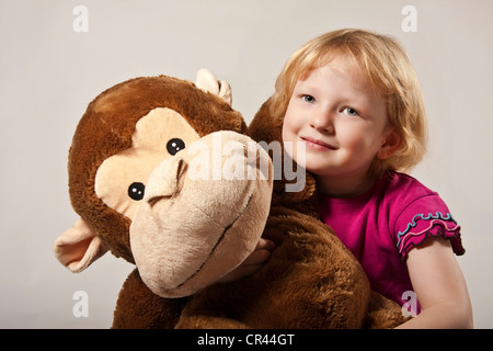 Ragazza, 5, con una scimmia ripiene Foto Stock