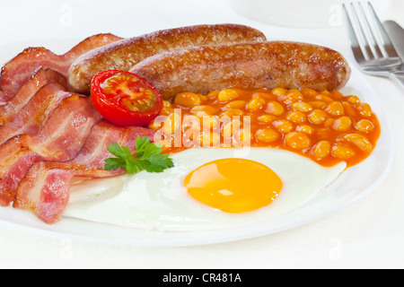 La completa prima colazione inglese, con pancetta, due salsicce, un uovo fritto, fagioli al forno e una metà di pomodoro. Foto Stock