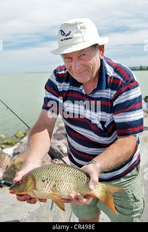 Pescatore con la sua cattura sulla scogliera del Balatonszemes marina sulle rive sud del Lago Balaton in Ungheria. Foto Stock