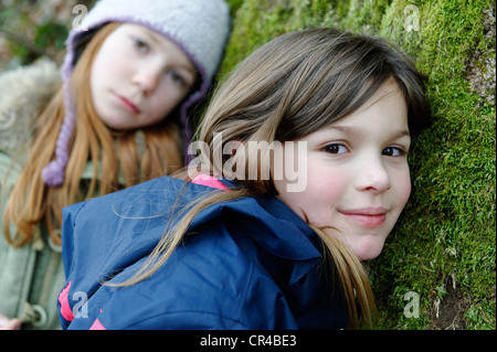 Due ragazze, amici, appoggiato su una struttura ad albero Foto Stock