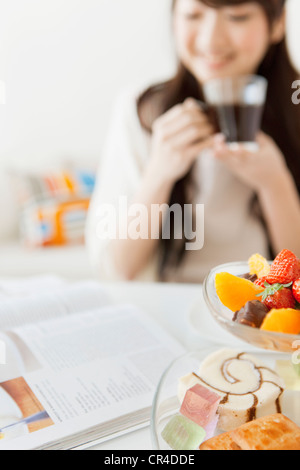 Giovane donna con tè e lettura di riviste Foto Stock