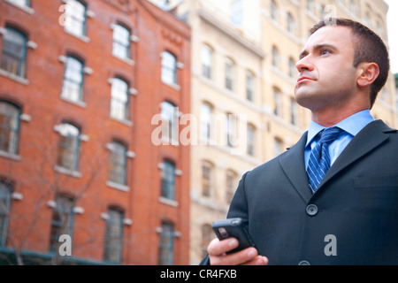 Ritratto di uomo caucasico in business suit utilizzando il telefono cellulare per le strade di New York City America Foto Stock