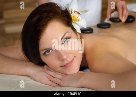 Donna con fiore a spa avente hot stone trattamento del dorso Foto Stock