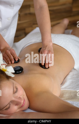 Donna con fiore a spa avente hot stone trattamento del dorso Foto Stock