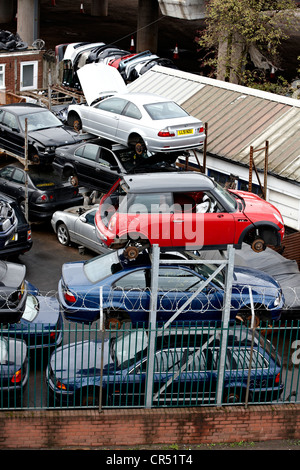 I rottami di automobili attendono lo smantellamento di una vettura breakers cantiere. Il metallo viene riciclato e quindi fatta in diversi prodotti Foto Stock