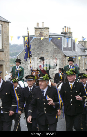 La Cornet e sostenitori seguire dietro Drum & Fife band per il Moro durante Hawick Common-Riding nella città di confine, Scozia Foto Stock