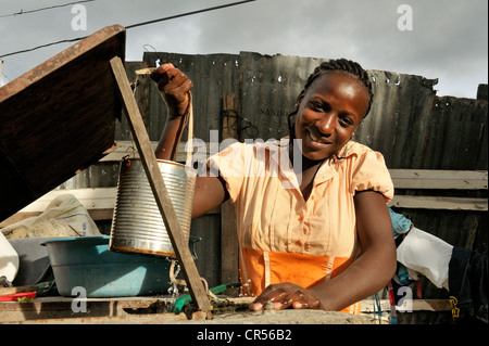 I giovani di carnagione scura donna recupero di acqua da un pozzo in un barattolo di latta, Port-au-Prince, Haiti, dei Caraibi e America centrale Foto Stock