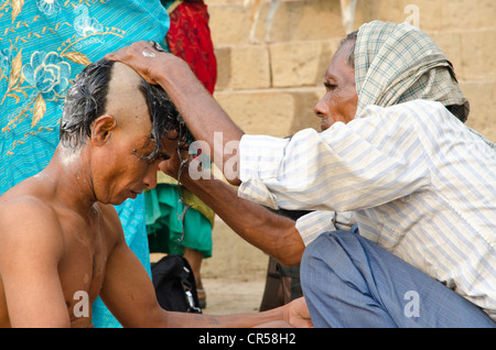 Testina di rasatura e la barba è parte del rituale per l'addio all'anima di una persona deceduta a ghats di , India, Asia Foto Stock