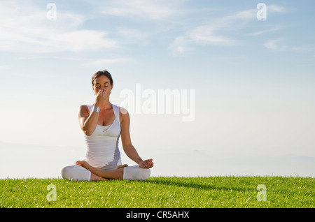 Giovane donna pratica di Hatha yoga all'aperto, che mostra la posa anuloma viloma, nadi shodhana pranayama Foto Stock