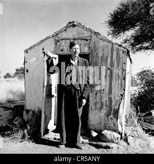 Sud Africa, anni '50, un supervisore miniera Afrikaner si trova all'esterno all'ingresso della sua abitazione di lavoro, una piccola capanna di legno o baracca in questa foto storica di J Allan Cash. Discendenti da coloni europei, soprattutto coloni olandesi ma anche francesi e tedeschi, nel XVII e XVIII secolo, gli africani come gruppo etnico in Sud Africa vennero a dominare la politica e il settore agricolo, nel paese, che durò fino al 1994. Foto Stock