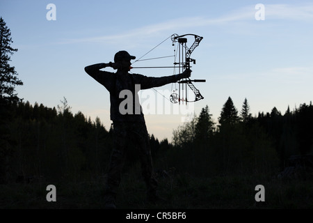 Silhouette di un moderno disegno bowhunter arco tornare nel bosco Foto Stock